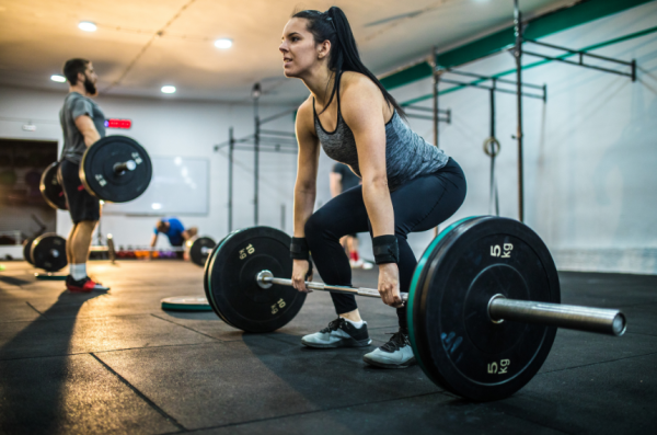 woman deadlifting with poor form causing pain from muscle imbalance